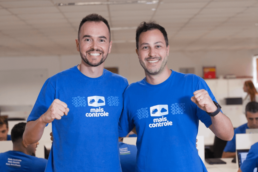 Co-fouders abraçados lateralmente com um dos braços levantados em gesto de vitória